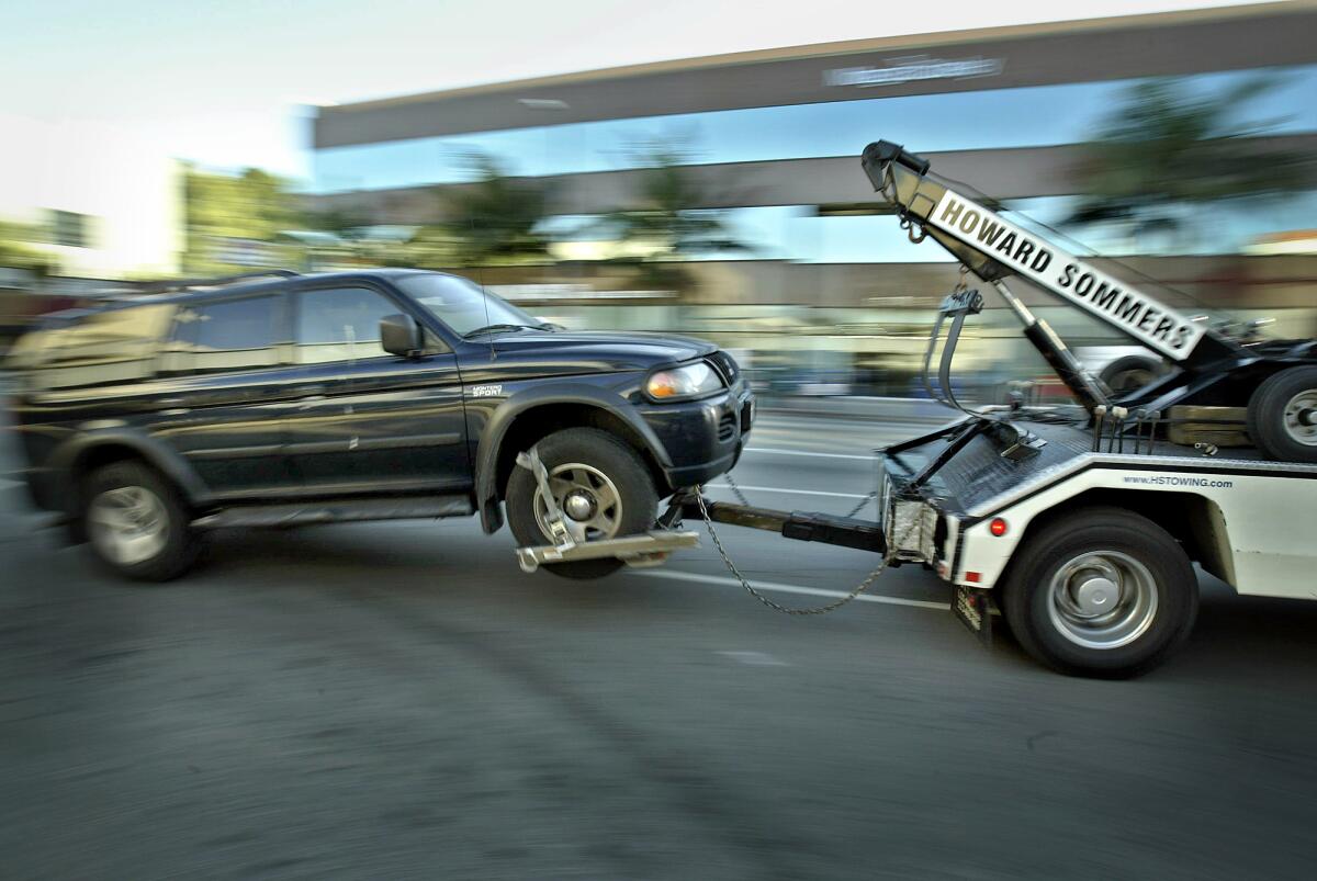 A tow truck drives off with a vehicle that is being impounded