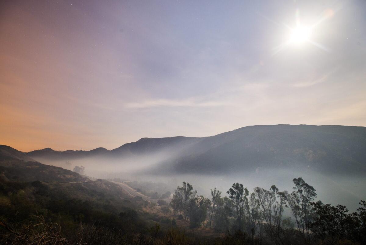 Smoke from the fires in San Marcos and Escondido lays down at dawn due to subsiding winds near Elfin Forest Road in San Diego County.
