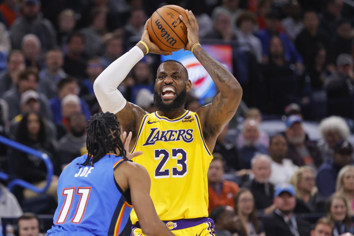 Lakers forward LeBron James calls to a teammate as he looks to pass while defended by Thunder guard Isaiah Joe.