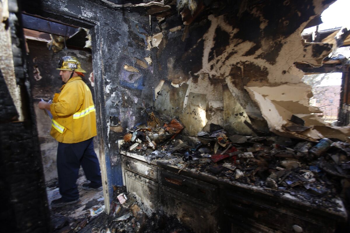 Jake Heflin, public information officer for the Long Beach Fire Department, walks through a heavily damaged apartment after an early-morning fire Thursday.