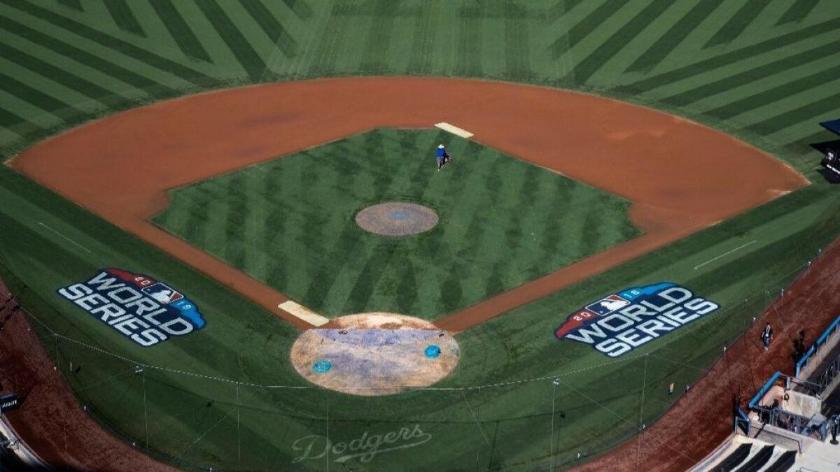 A grounds crew member gets his grass lines in sync on the field for Friday's Game 3 of the World Series at Dodger Stadium.