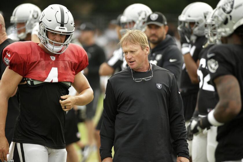 Oakland Raiders head coach Jon Gruden talks with quarterback Derek Carr during NFL football practice Wednesday, Aug. 8, 2018, in Napa, Calif. Both the Oakland Raiders and the Detroit Lions held a joint practice before their upcoming preseason game on Friday. (AP Photo/Eric Risberg)