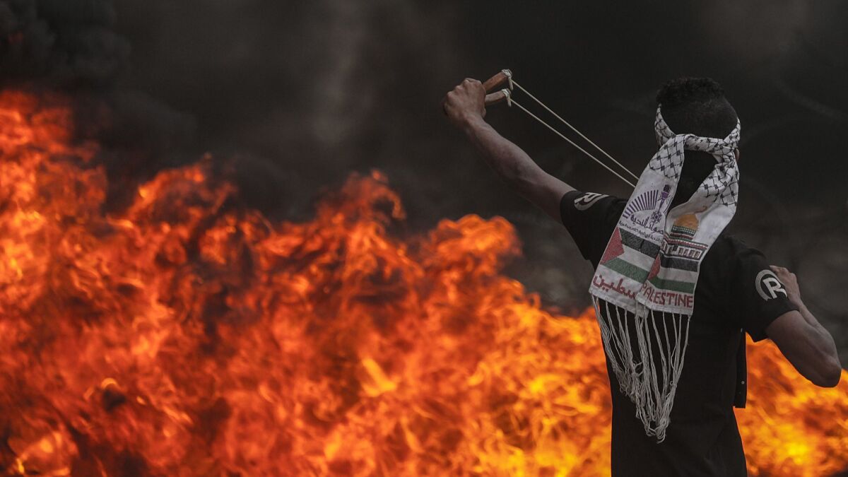 A Palestinian protester deploys stones with a slingshot during clashes along Gaza-Israel border fence.