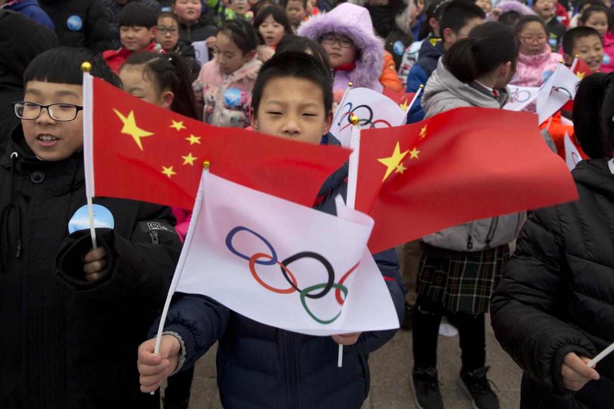 A child waves a Chinese national flag and an Olympic flag during a ceremony in February 2018 for the 2022 Winter Olympic Games in Beijing.