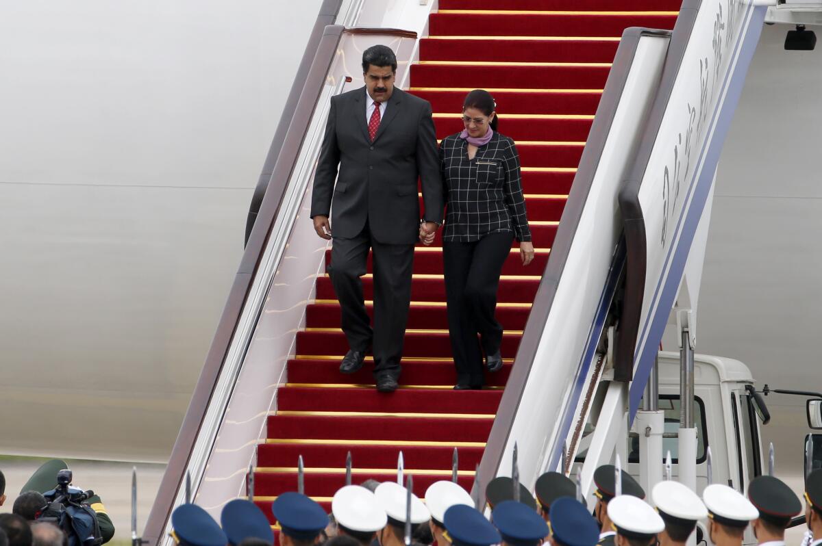 Venezuela's president and first lady walk down the steps of an airplane.