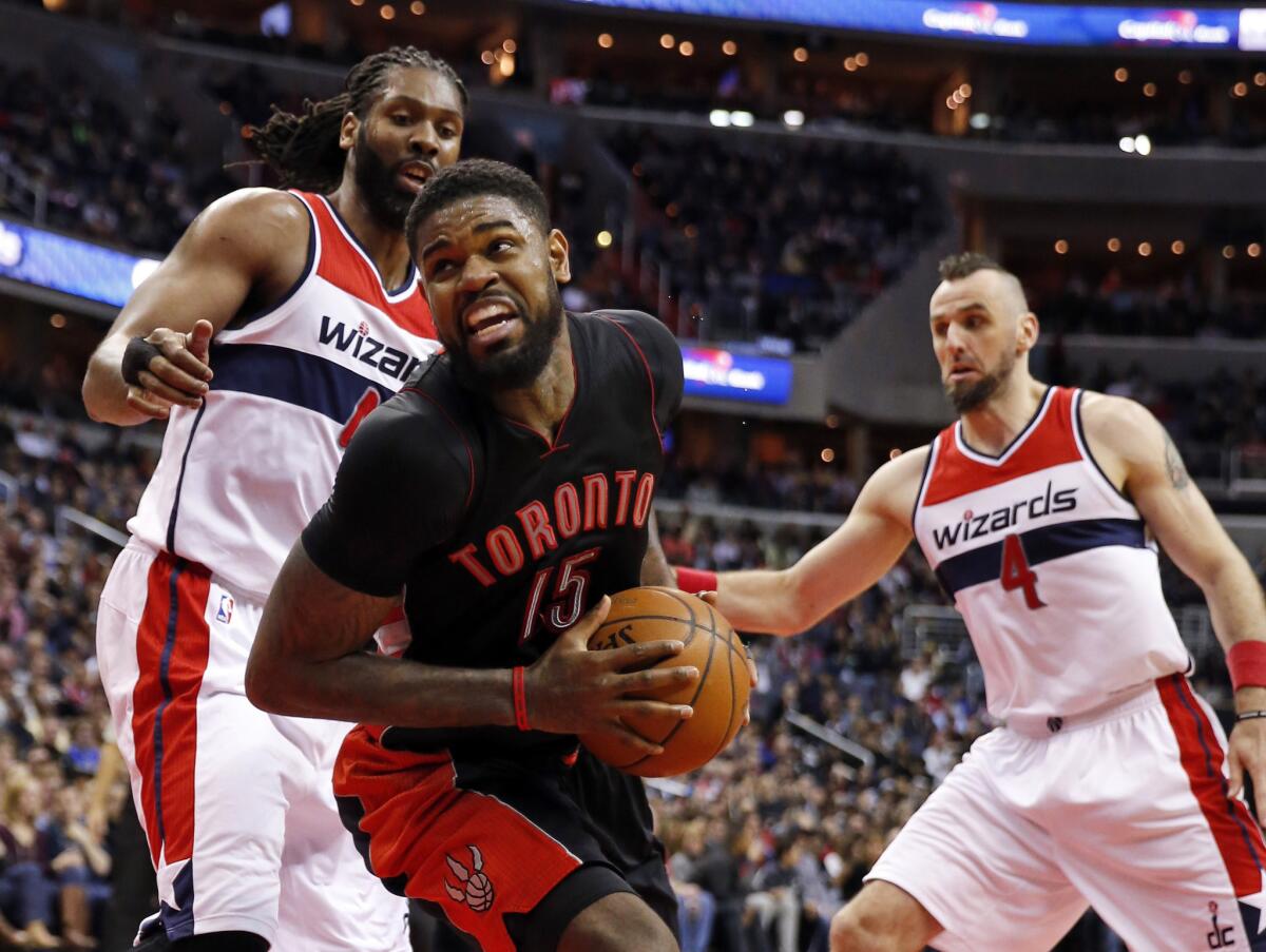 Toronto forward Amir Johnson spins away from Washington forward Nene, left, and center Marcin Gortat during the first half of the Raptors' 120-116 overtime victory Saturday over the Wizards.