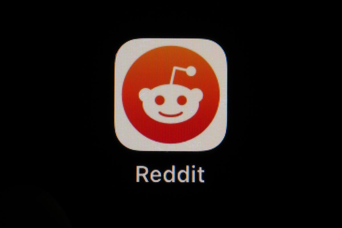 The Reddit app icon of a face with an antenna on top of it is seen on a smartphone.