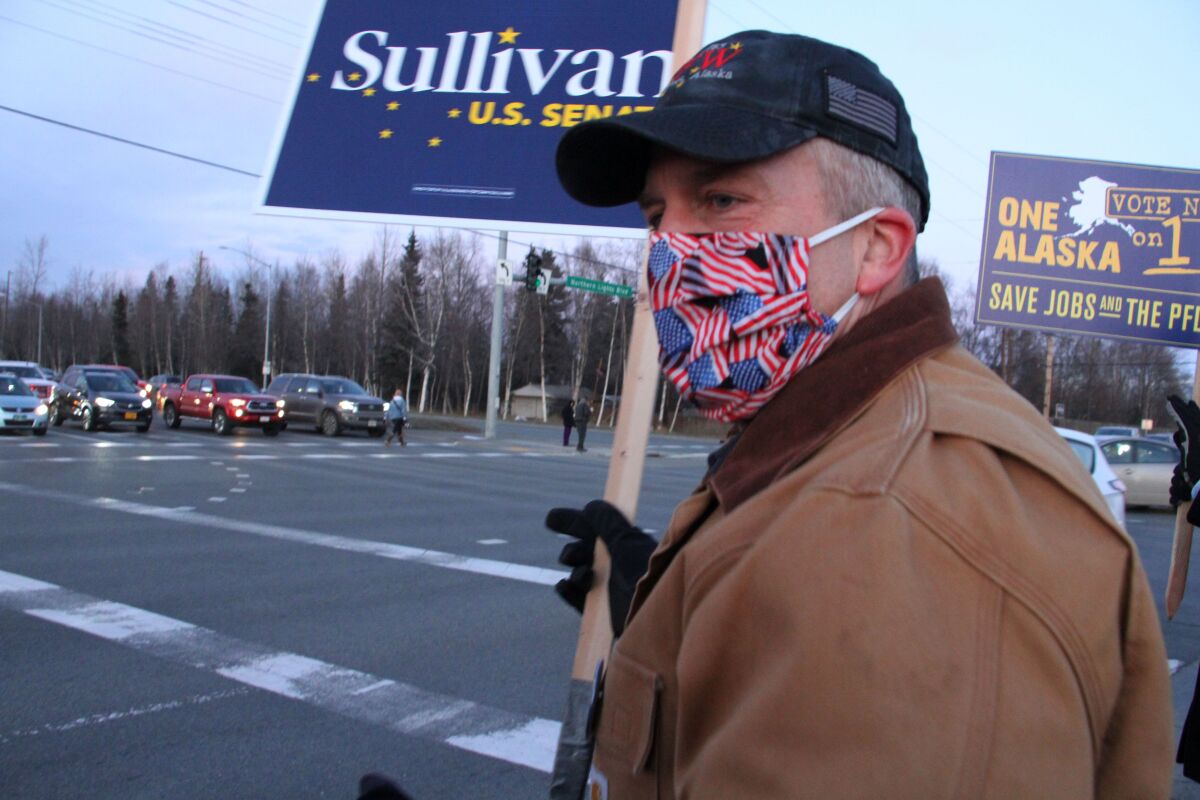 FILE - In this Nov. 2, 2020, file photo, Republican U.S. Sen. Dan Sullivan waves a sign at a busy intersection in Anchorage, Alaska. Sen. Sullivan on Wednesday, Nov. 11, 2020, won re-election in Alaska, defeating independent Al Gross. (AP Photo/Mark Thiessen, File)