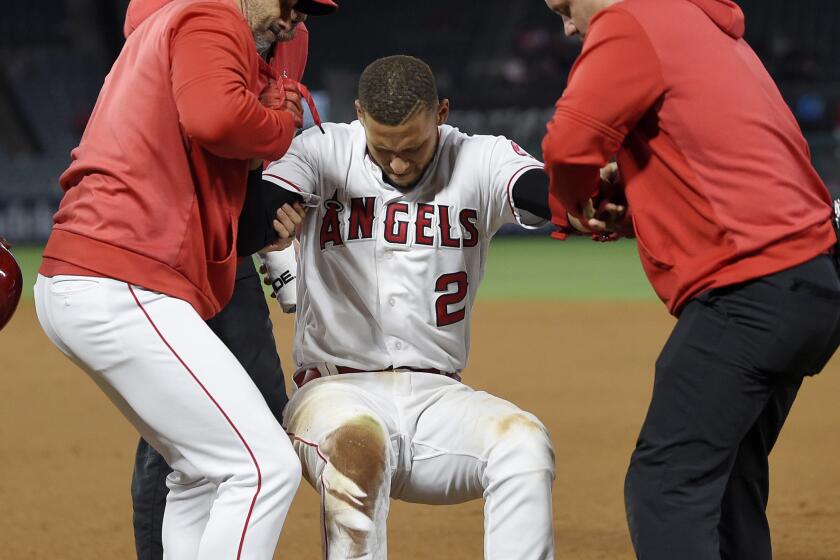 Los Angeles Angels' Andrelton Simmons, center, is helped up by manager Brad Ausmus, left, and a trainer after he was injured while being thrown out at first during the eighth inning of a baseball game against the Minnesota Twins Monday, May 20, 2019, in Anaheim, Calif. (AP Photo/Mark J. Terrill)