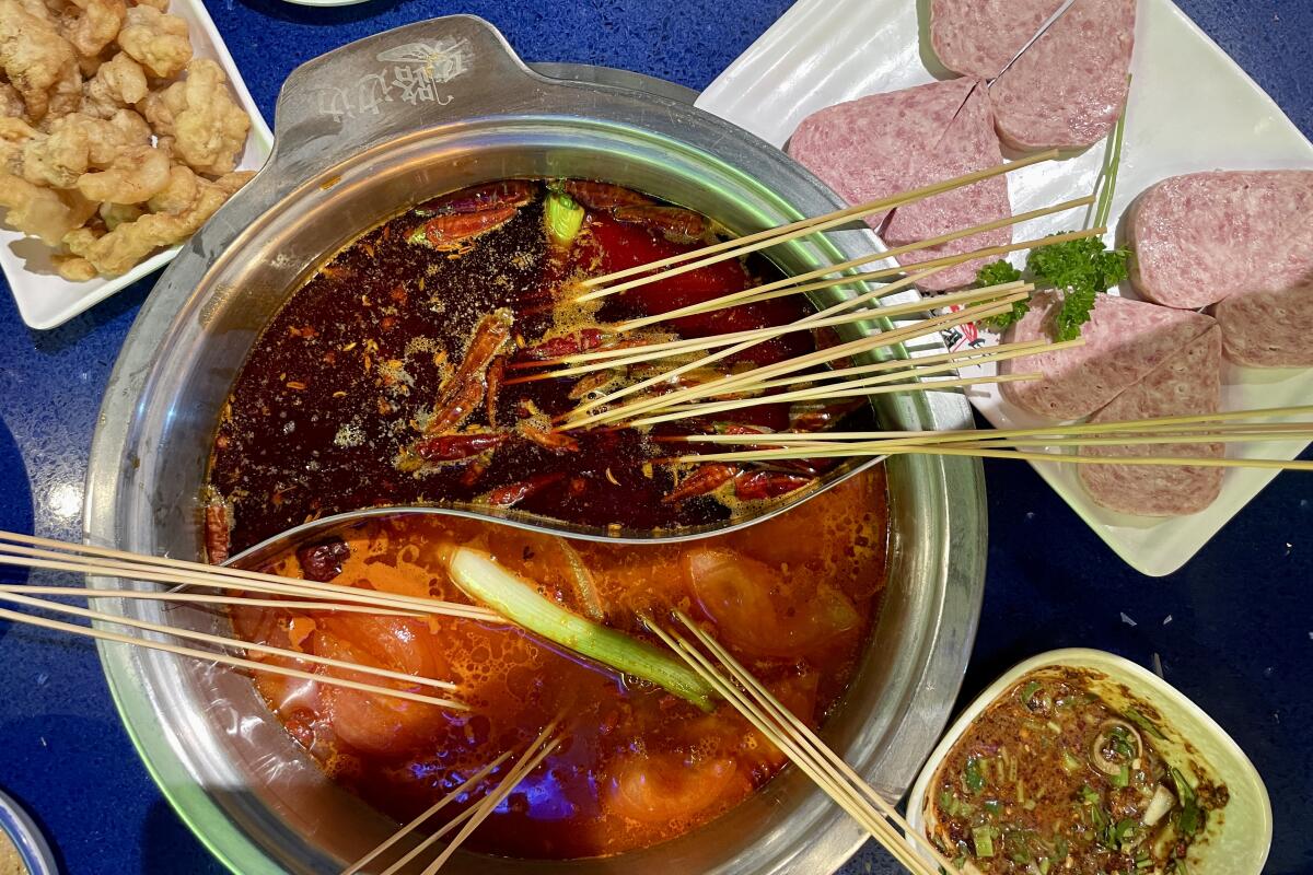 Hot pot with skewers of meat and shrimp alongside a plate of heart-shaped house-made Spam from Ma Lu Bian Bian in Tustin