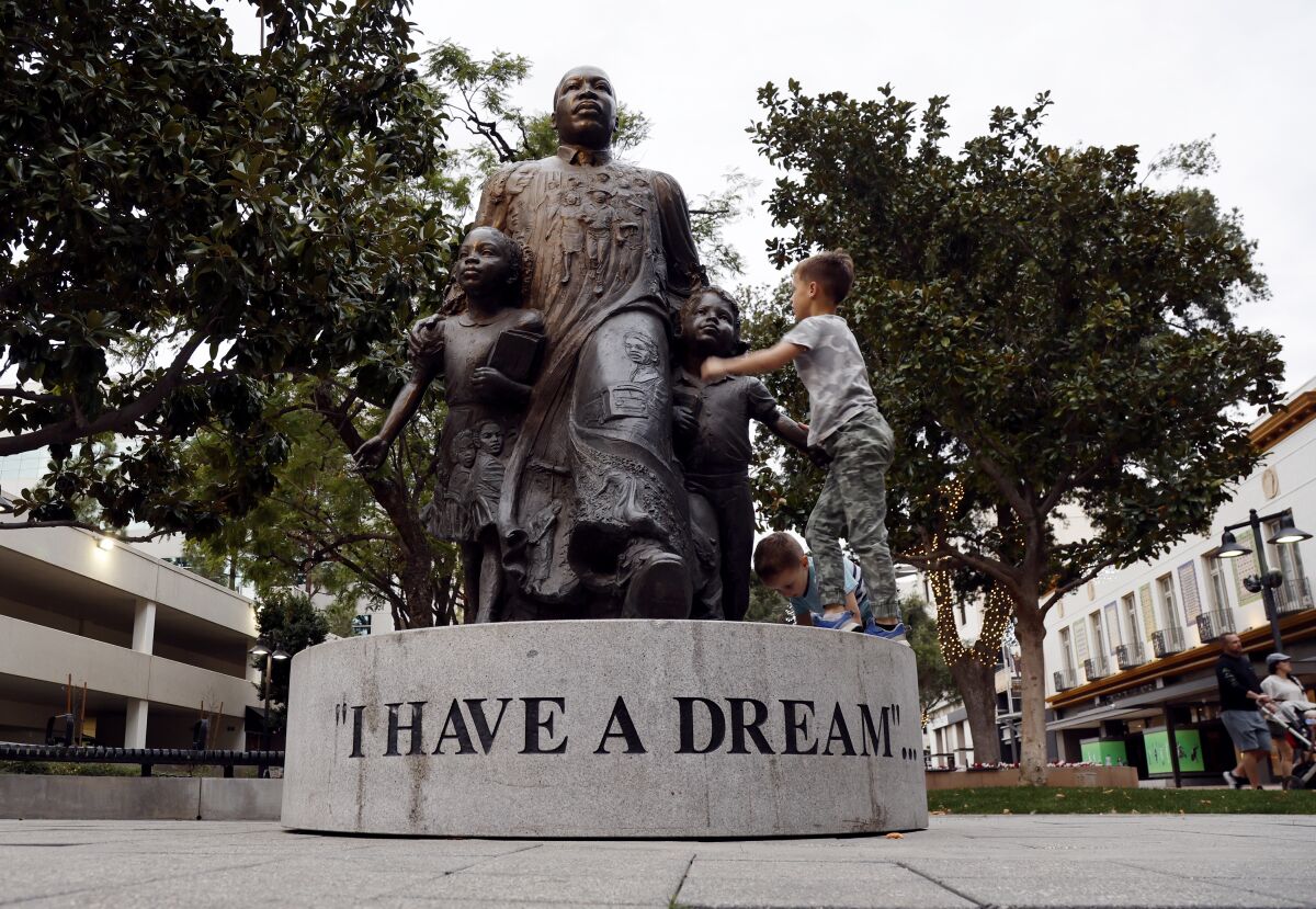 Youngsters climb on the pedestal of the Martin Luther King "I Have a Dream" statue in Riverside in 2022.