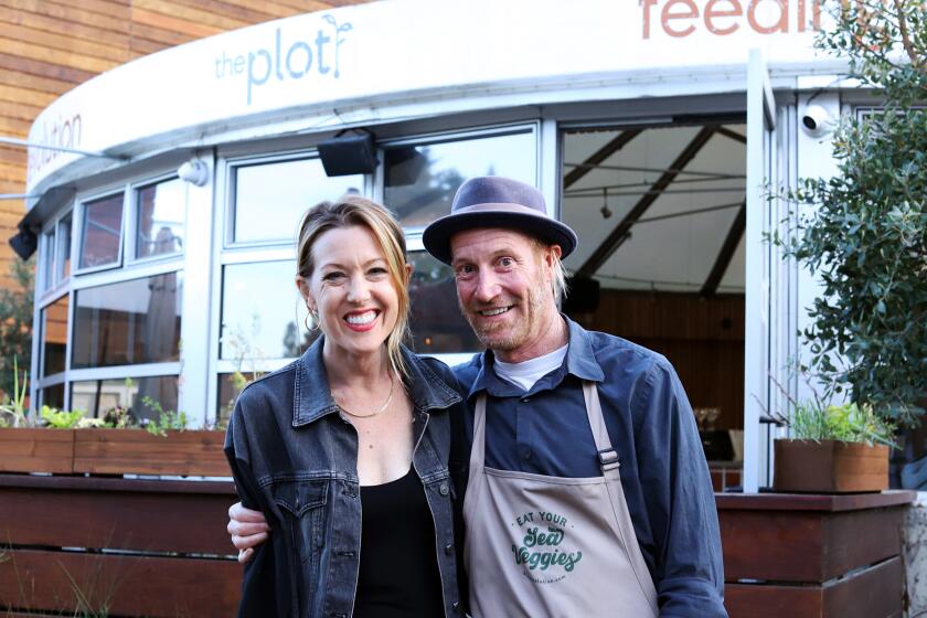 The owners of The Plot restaurant husband and wife duo Jessica and Davin Waite pose in from of their restaurant located in the Camp in Costa Mesa on Thursday, March 28, 2024. The Plot is a plant-forward restaurant with restaurants in Oceanside, Carlsbad and now in Costa Mesa, with zero-waste practices they produce their product from their own regenerative garden. (Photo by James Carbone)