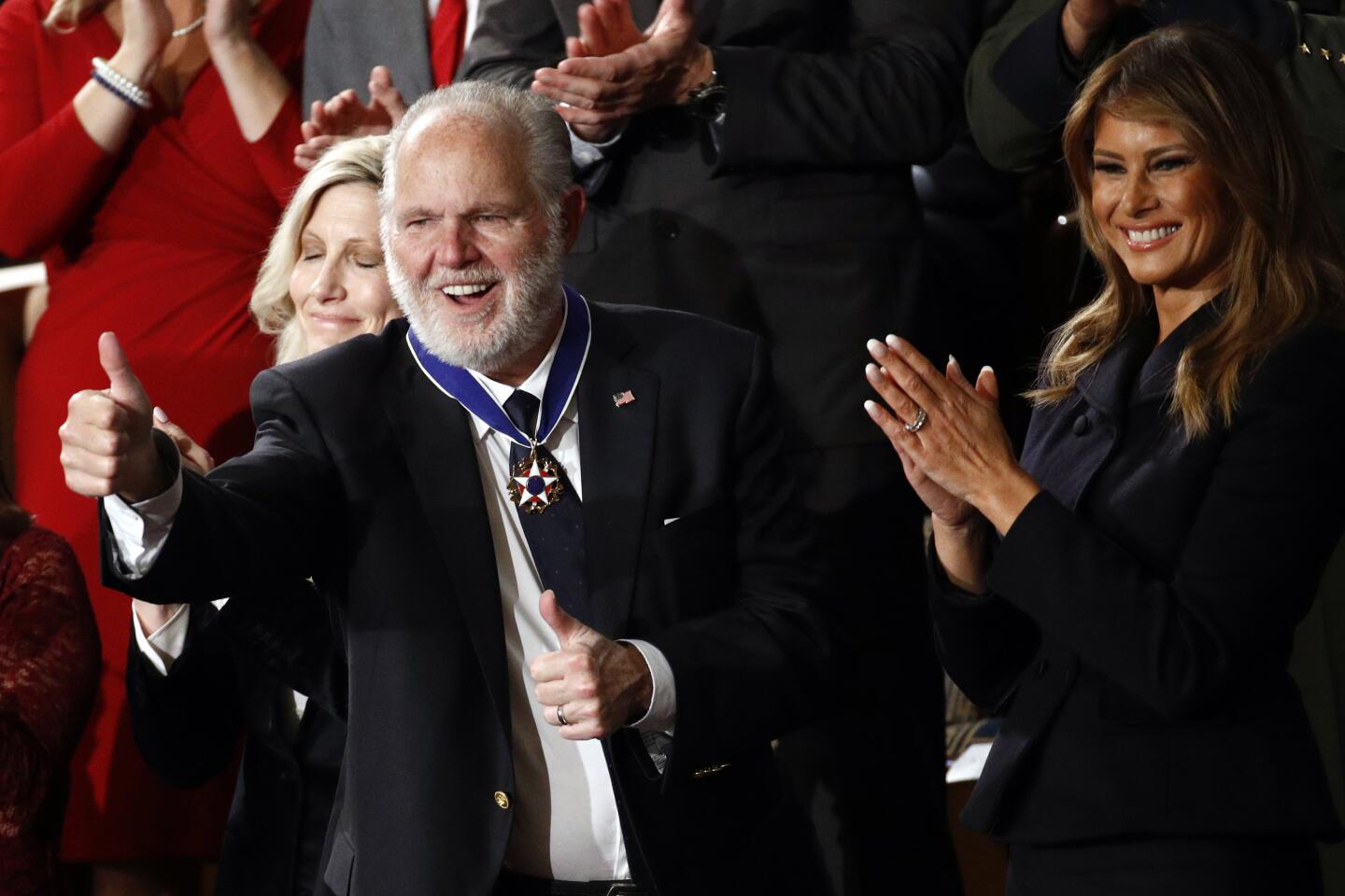 Rush Limbaugh, medal around his neck, holds both thumps up.