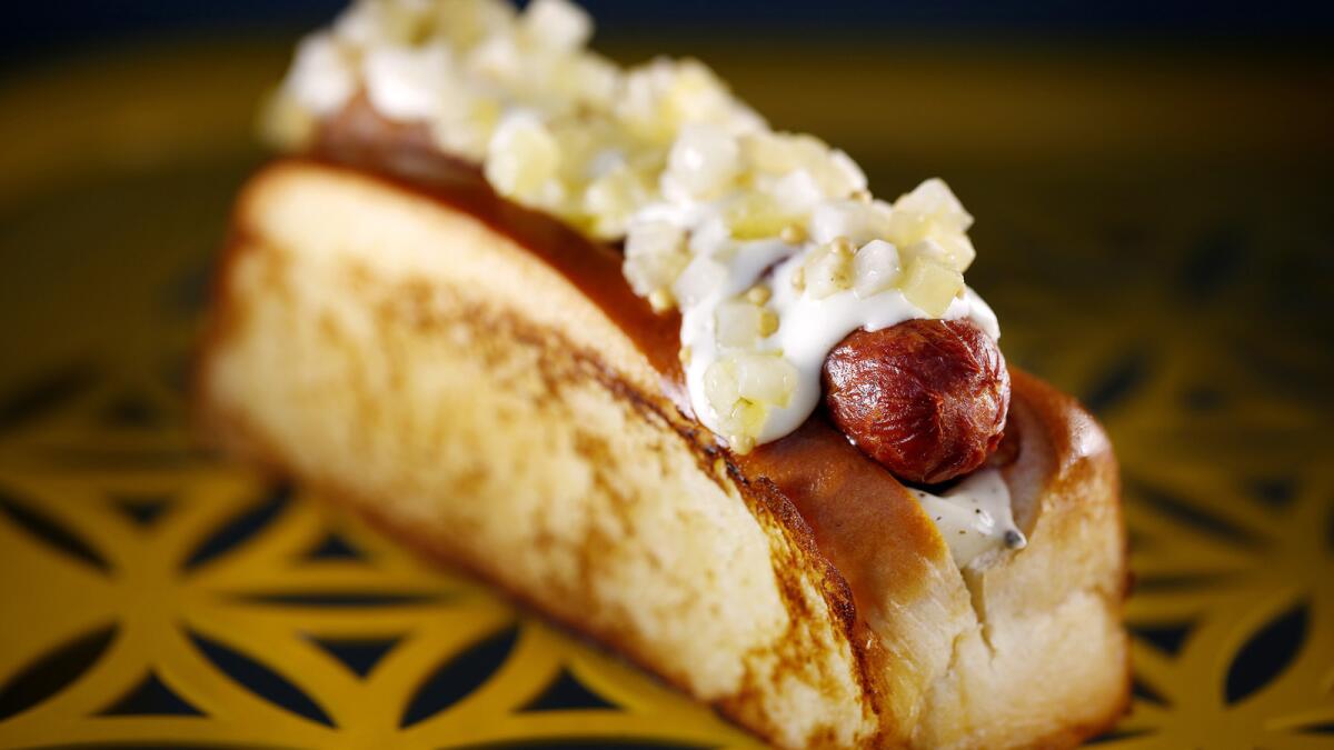 The Humm Dog is a bacon-wrapped hot dog with black truffle mayonnaise, cheese sauce and celery relish with pickled mustard seed.