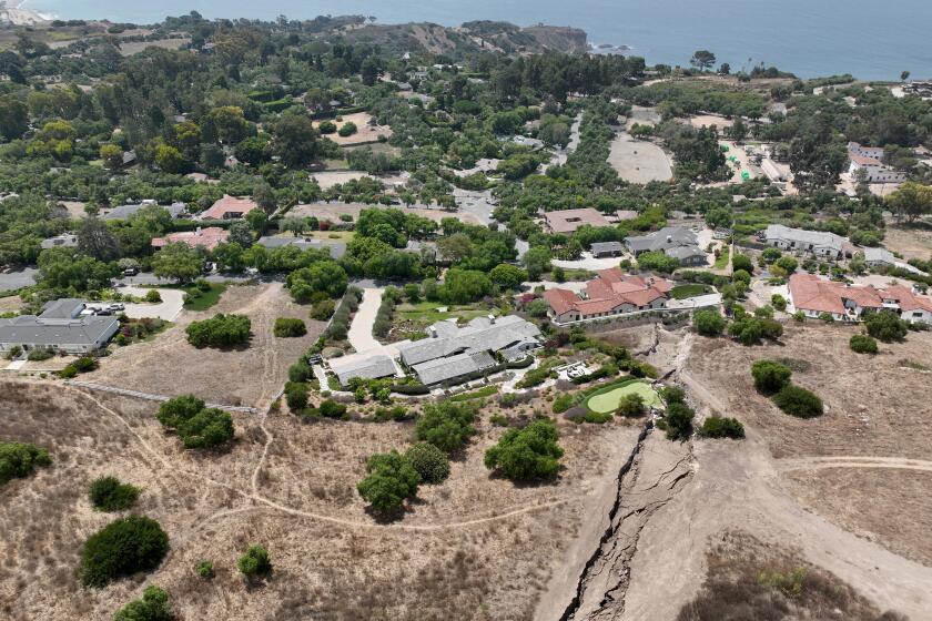 Rancho Palos Verdes, CA - August 01: An aerial view of a large fissure that has opened up since February, damaging a Portuguese Bend putting green and home after last winter's heavy rain in Rancho Palos Verdes Thursday, Aug. 1, 2024. Due to continual land movement, the Portuguese bend neighborhood in Rancho Palos Verde could face power shut off. Mike Hong, whose home neighbors a large fissure that has been getting larger and deeper since February, when the area was inundated with heavy rains. He says that water is draining from Rolling Hills homes into Altamira Canyon and directly flowing into the earth and not into the ocean, which is part of a proposed drainage plan. He says lining the canyon would help as rain saturation is one of the contributing factors to movement in the area. The fissure also passes through and through the Palos Verdes Nature Preserve. (Allen J. Schaben / Los Angeles Times)