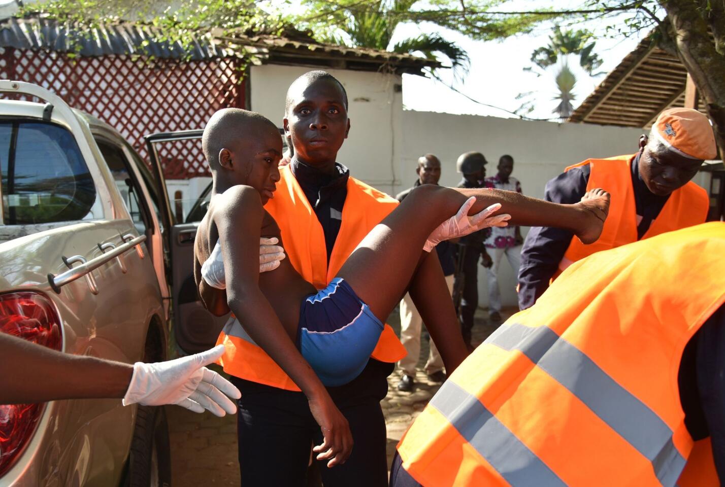 An emergency worker carries a young boy who was injured during an attack on the beach at the hotel Etoile du Sud in Grand Bassam on March 13, 2016.
