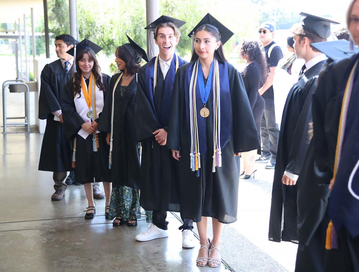 Early College High School grad Marcelina Sanchez, right, walks in a commencement ceremony with classmates at OCC Thursday.