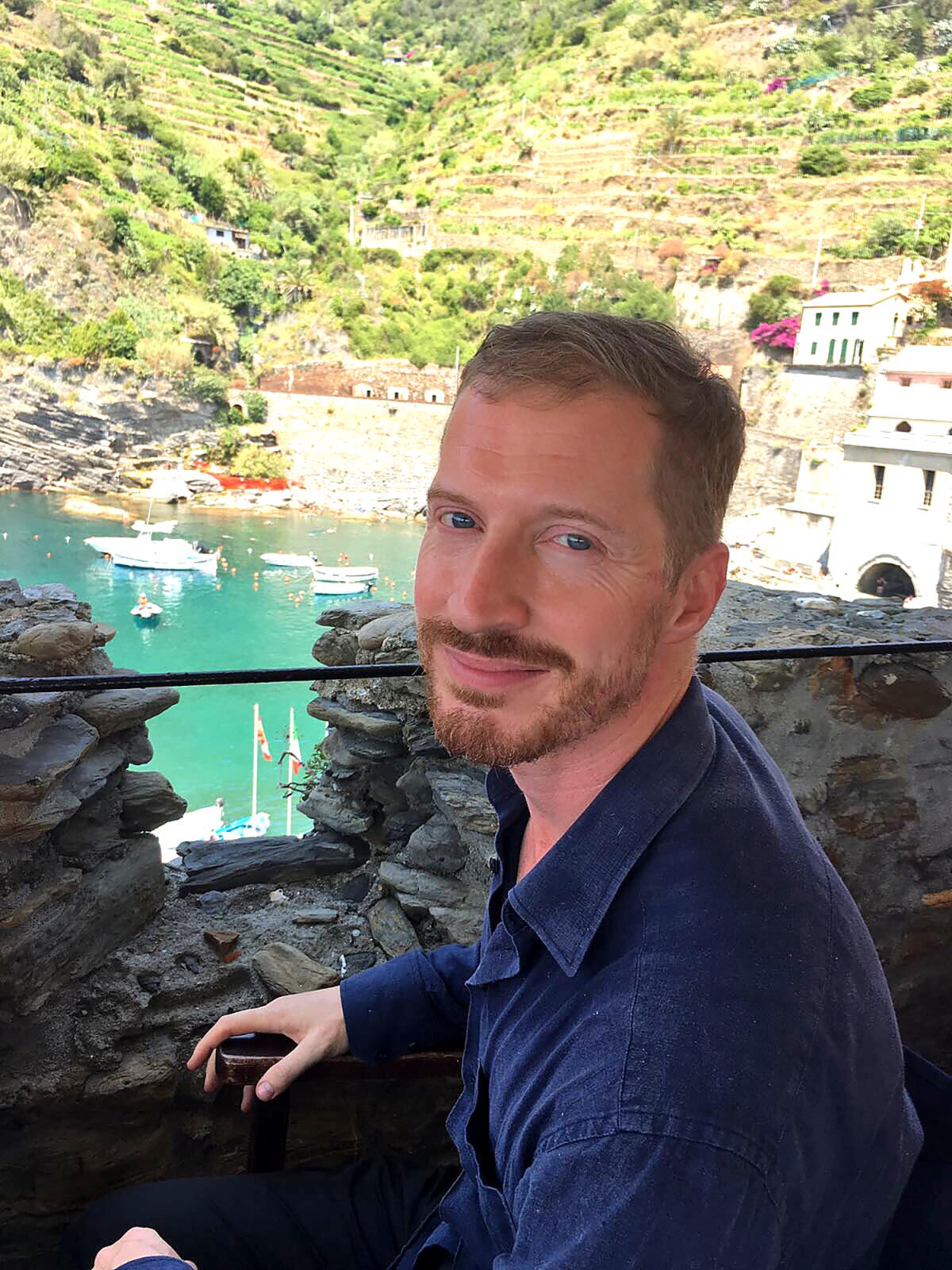 A man on a stone balcony overlooking water