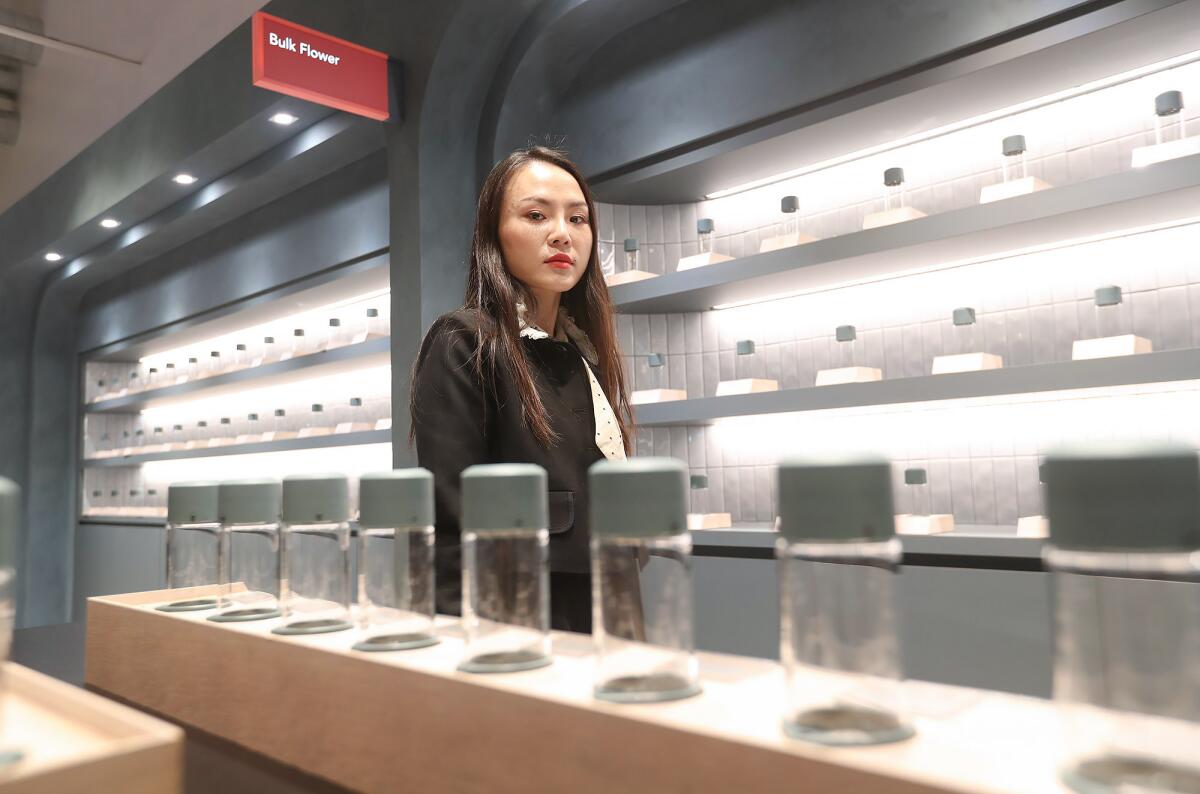 Rachel Xin stands with rows and shelves of empty containers of no product.