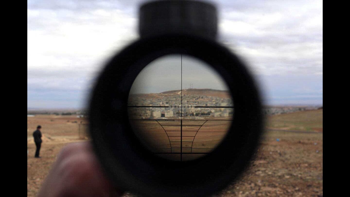 A man watches the Syrian town of Kobani through a sniper rifle sight near the Mursitpinar border crossing in Turkey.