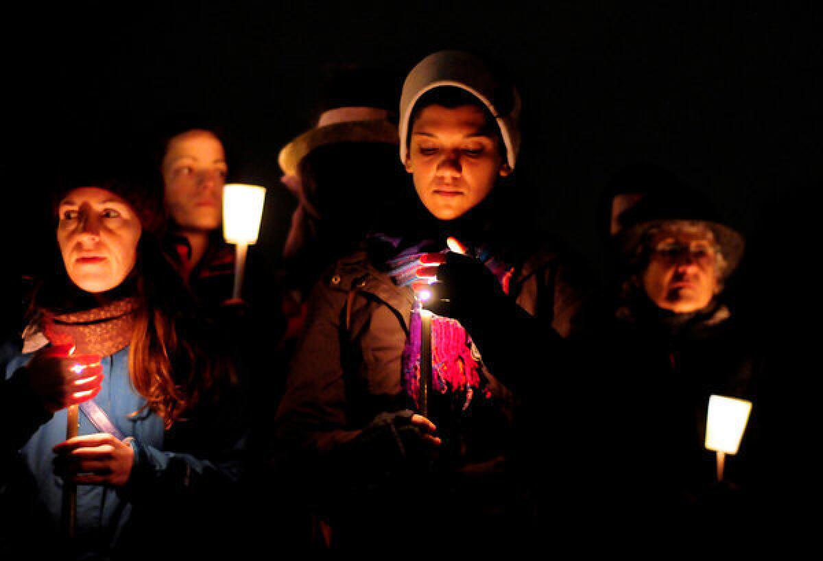 People shield their candles from the wind and light rain during a candlelight vigil in remembrance of the Newton, Conn. shooting victims at Green Lake Park in Seattle.