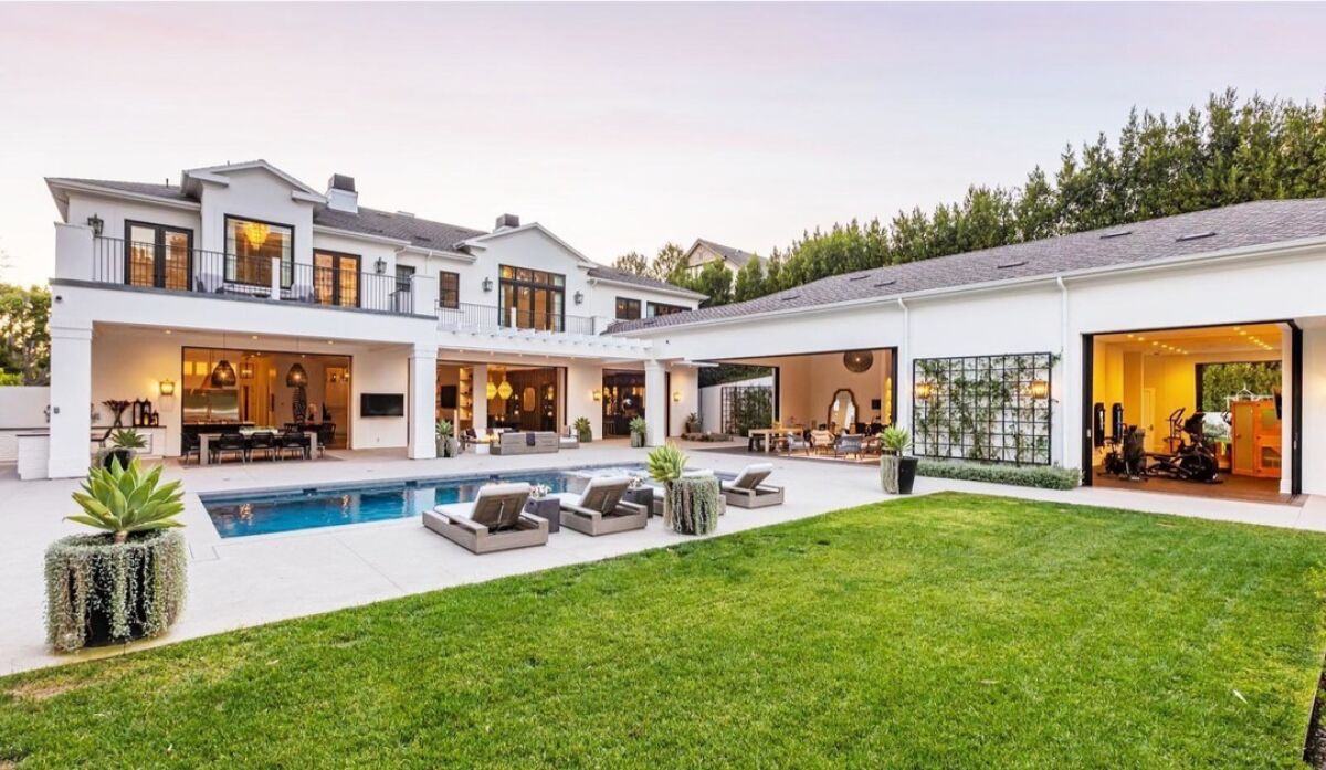 Exterior of the house showing lawn, pool, rooms in the house open to a view of furnishings.