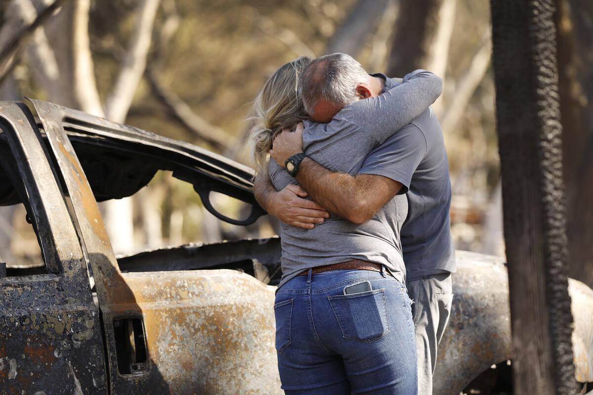 David Carr cries as he hugs his partner, Rachael Bailey, at the site of their home in the Oak Forest Mobile Estates in Westlake Village.