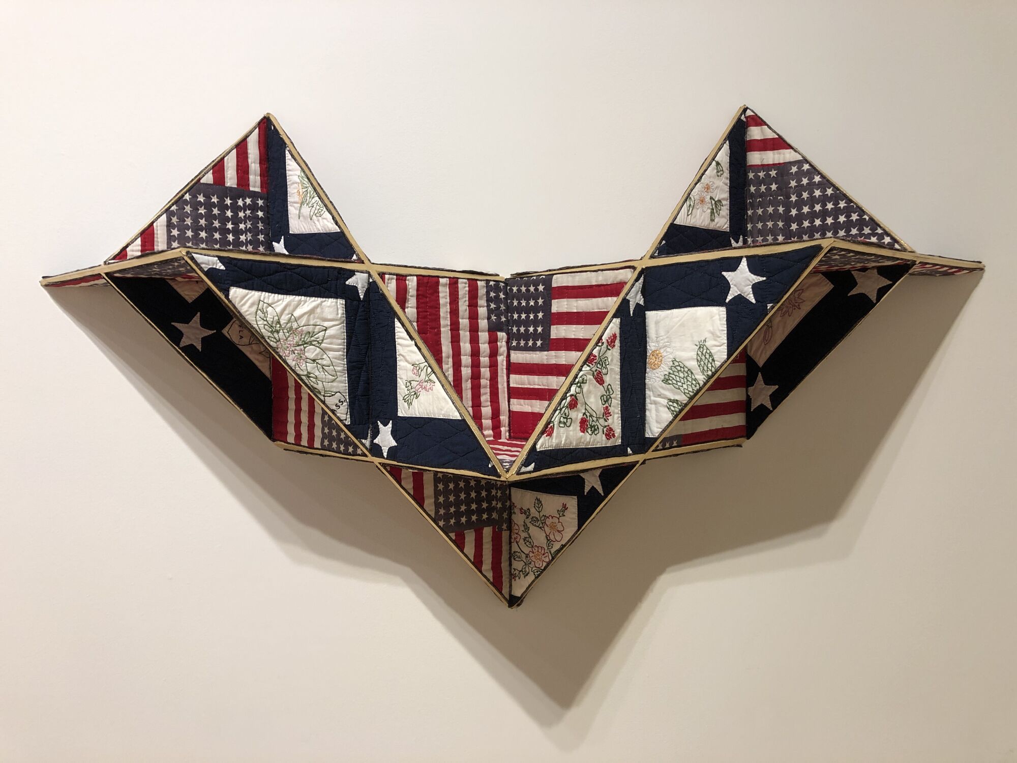 A work of geometric sculpture titled "Reconstruction" employs patches of old quilts and American flags.