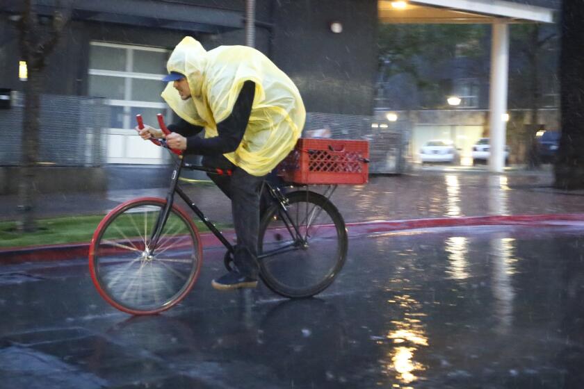 As the rain fell early Friday evening, a bicyclist rode along Island Avenue in East Village.