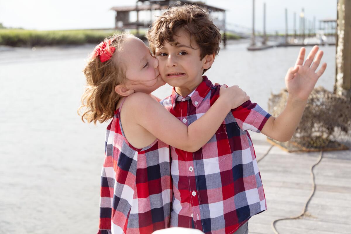 A boy and a girl embracing on the water front.
