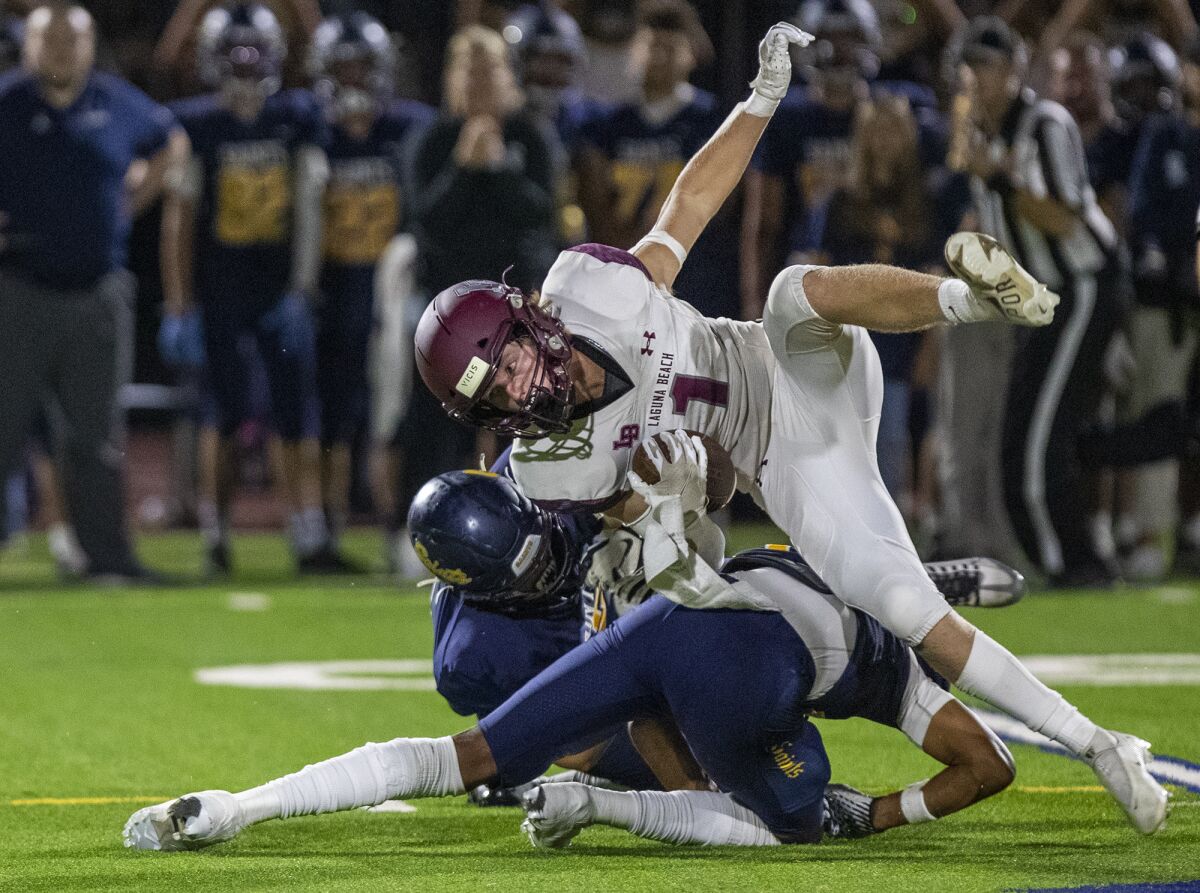 Laguna Beach's Nick Rogers is upended by Crean Lutheran's Ty Benefield, left, and Kellen Cosenza during a game on Friday.