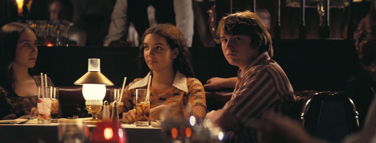 Two girls, left, and a boy sit at a restaurant table 