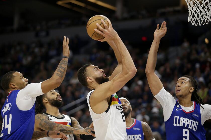 Timberwolves center Rudy Gobert shoots between the Clippers' Norman Powell (24), left, and Moses Brown (9) on Jan. 6, 2023.