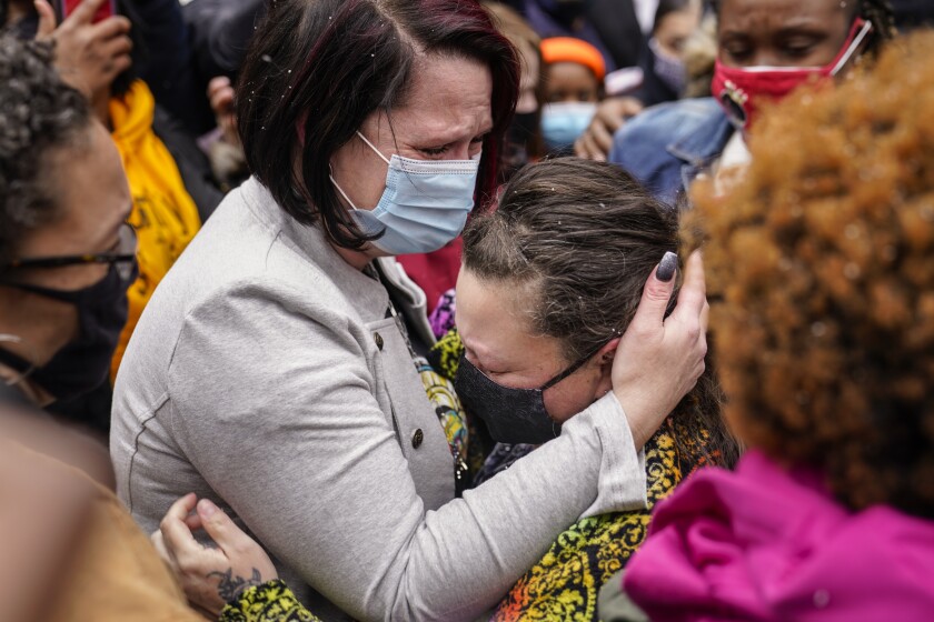 Two people wearing masks hug