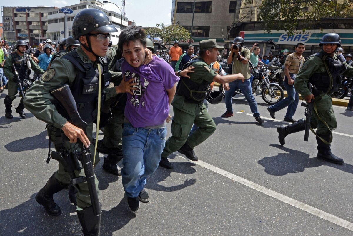 Venezuelan National Guard members in Caracas arrest a demonstrator during a protest against the government of President Nicolas Maduro and to protect him from being attacked by pro-Maduro motorcyclists.