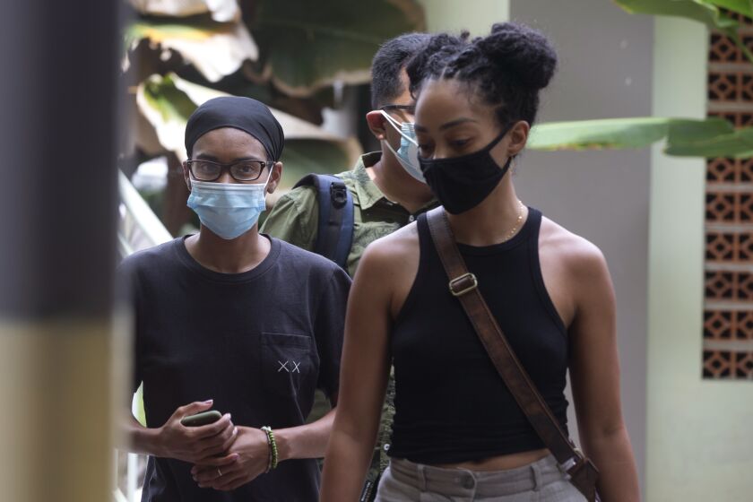 American graphic designer Kristen Antoinette Gray, left, walks with her partner Saundra Michelle Alexander, right, to be tested for the coronavirus at a hospital in Denpasar, Bali, Indonesia on Wednesday, Jan. 20, 2021. Gray, who arrived in Bali in January 2020 and wound up staying through the coronavirus pandemic, is being deported from the Indonesian resort island over her viral tweets that celebrated it as a low-cost, queer-friendly place for foreigners to live. (AP Photo/Firdia Lisnawati)