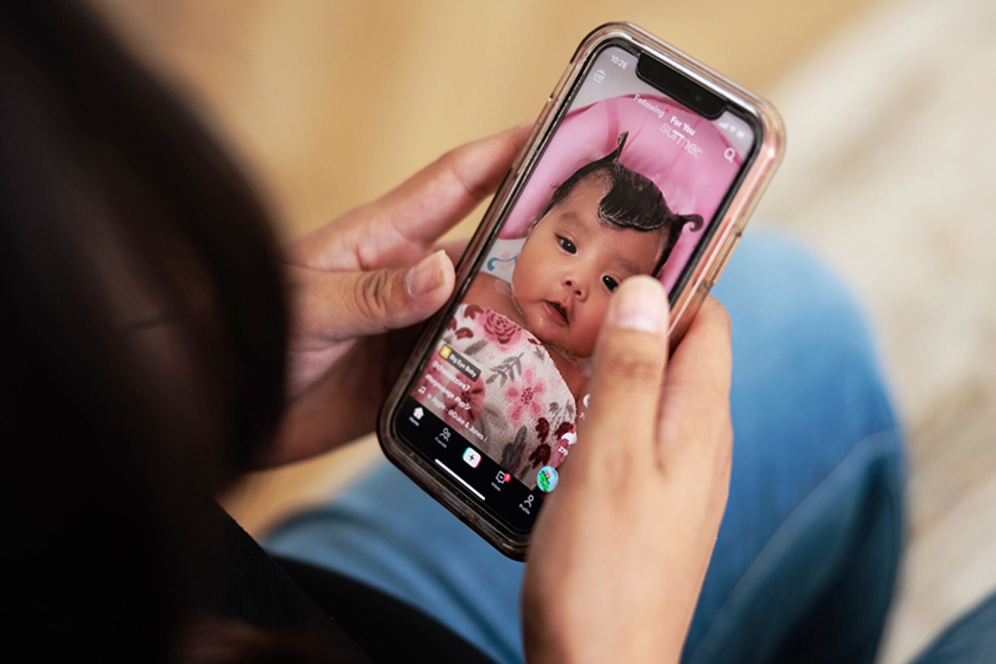 A woman looks at a baby's face on her TikTok feed.