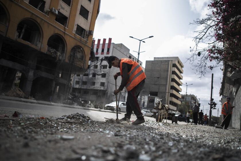 Palestinian municipal workers clean the streets following a cease-fire reached after an 11-day war between Gaza's Hamas rulers and Israel, in Gaza City, Friday, May 21, 2021. (AP Photo/Khalil Hamra)