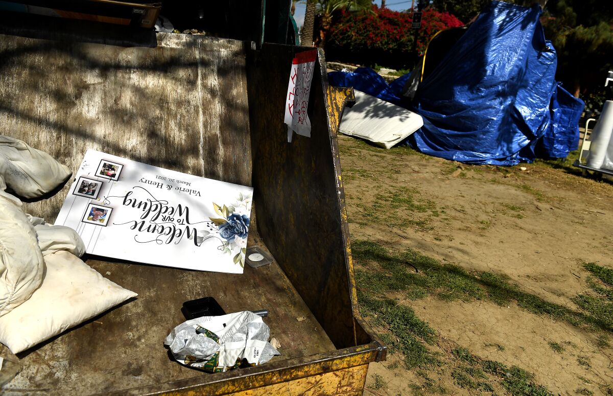 A wedding sign sits in a trash bin ready to be hauled away.