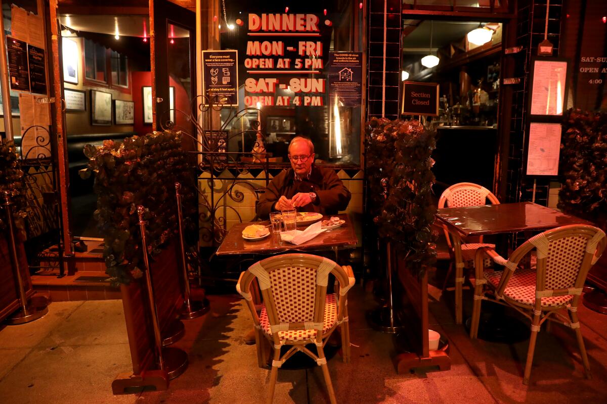 A man sits alone at a table outside a restaurant