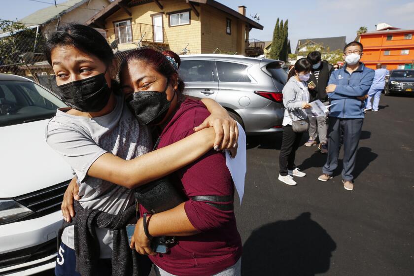 LOS ANGELES, CA - APRIL 20: Jeymy Mendoza, 16, hugs her mother Maria Jimenez, 34, as they wait in line to receive the Pfizer Covid-19 vaccination at a new, walk-up mobile COVID-19 clinic launched today to provide the Pfizer COVID-19 vaccine to underserved communities in Los Angeles. The walk-up clinic was presented by Councilmember Mark Ridley-Thomas in partnership with CHA Hollywood Presbyterian Medical Center (CHA HPMC) and the Southern California Eye Institute (SCEI). The Mobile Vaccine Clinic at 1819 S. Western Avenue will be open every Tuesday starting April 20 through May 25 providing free vaccines to community members who are eligible per LA County Department of Public Health (LAC DPH) vaccine distribution guidelines as they partnered with Charles R. Drew University of Medicine and Science to provide student volunteers for on-site registration allowing for walk-up appointments for community members and further ensuring vaccine access in our hardest-hit communities. Los Angeles on Tuesday, April 20, 2021 in Los Angeles, CA. (Al Seib / Los Angeles Times).