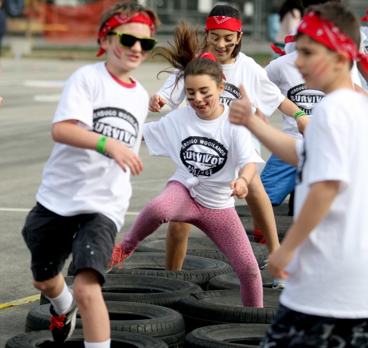 Fifth-grade teacher Katie Turner's students, including Lillian Mehrabians, center, goes through the tire obstacle course at Verdugo Woodlands Elementary School's annual Survivor Challenge fundraiser, at the school in Glendale on Friday, March 4, 2016.