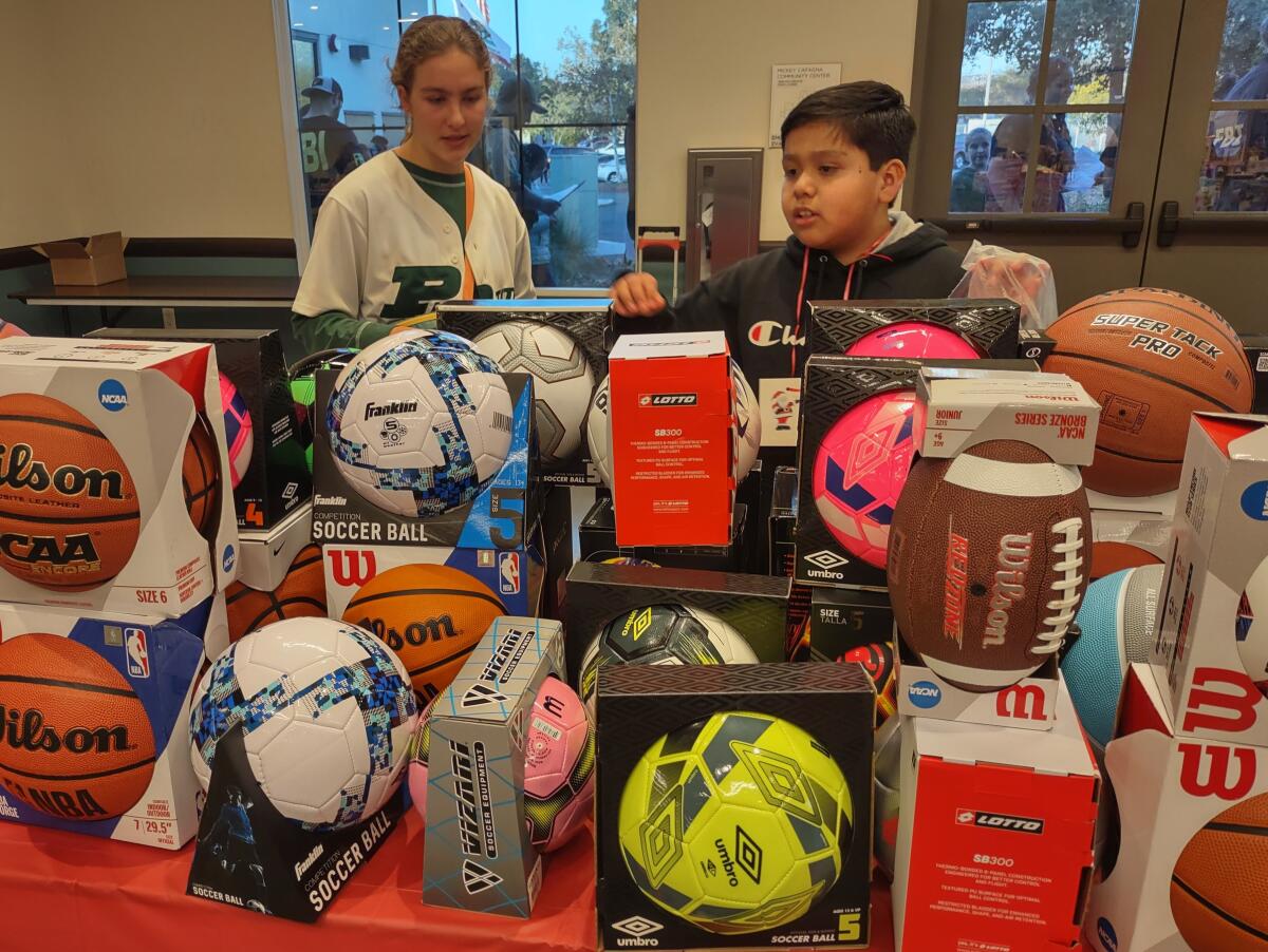 Anjolie Norton helps Jose Martinez pick out a soccer ball and a football as gifts for his brothers.