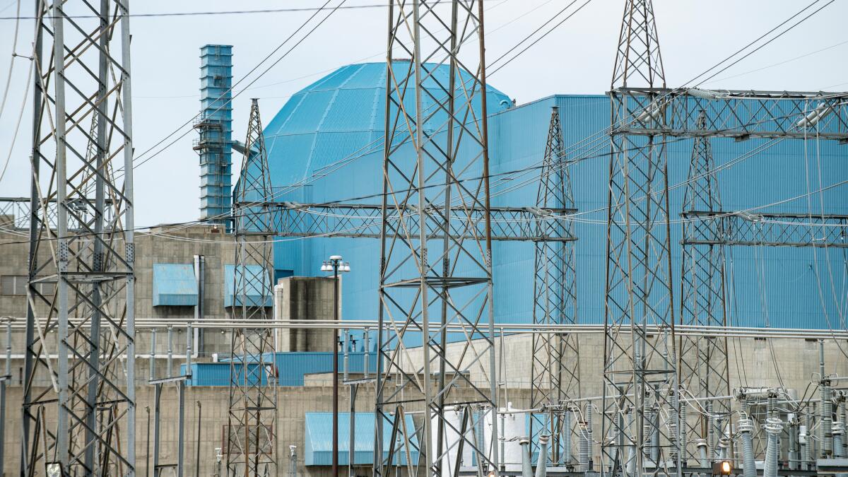 A nuclear power plant in Clinton, Ill. is seen through a tangle of high voltage power lines on June 2. The plant's parent company, Exelon, announced that it would close the plant in 2017.