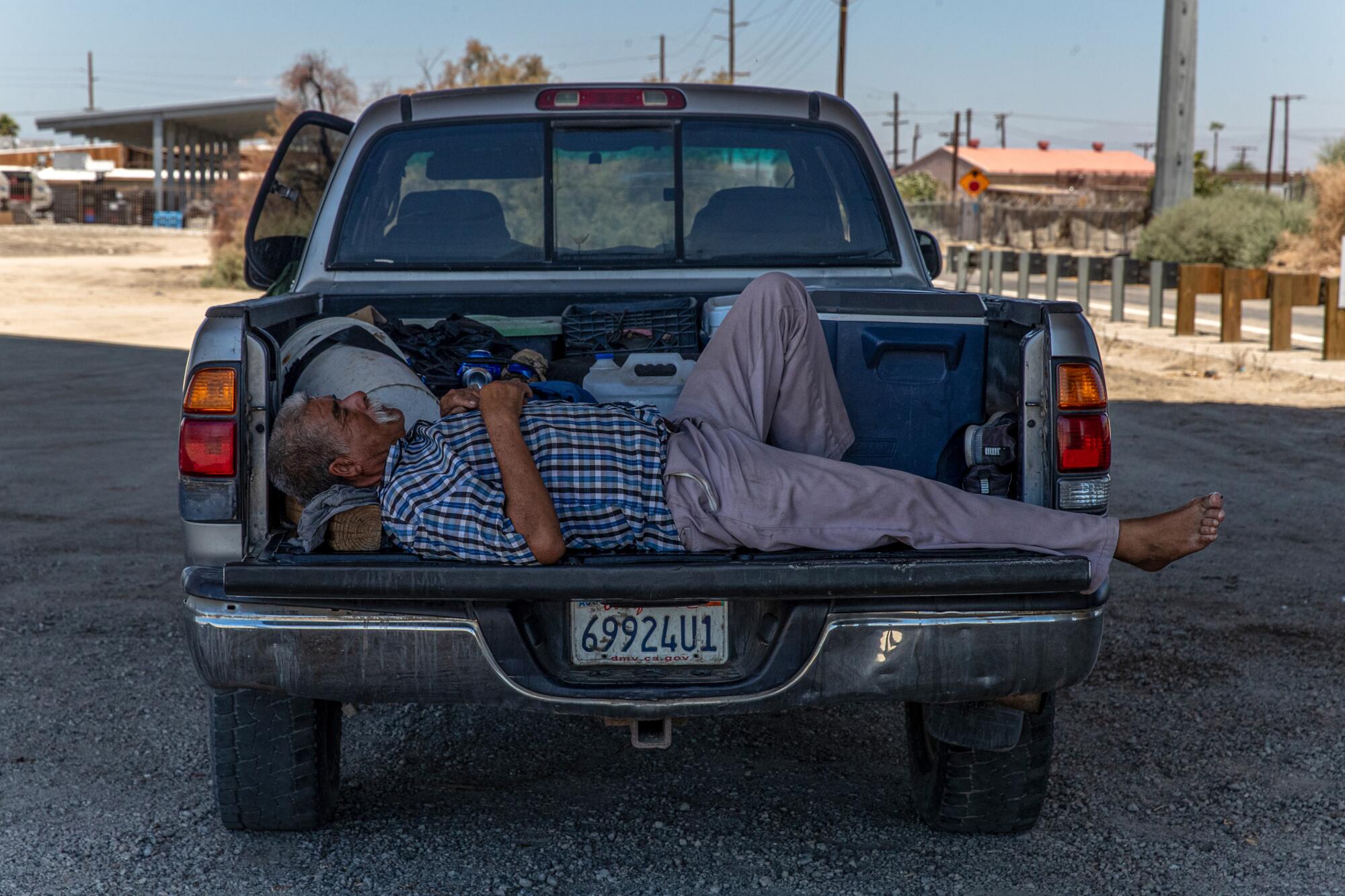 A farmworker sleeps in a pickup truck in the shade of the Avenue 66 Bridge in Mecca, Calif.