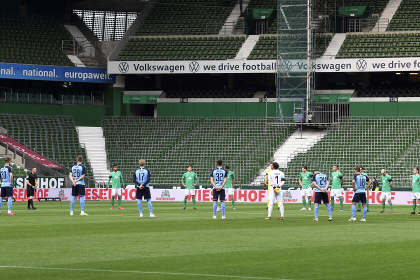 Players stand during a minute's silence for the victims of the coronavirus before the soccer match between Werder Bremen and Borussia Moenchengladbach in Bremen, Germany, Tuesday May 26, 2020. The German Bundesliga is the world's first major soccer league to resume after a two-month suspension because of the coronavirus pandemic. (Fabian Bimmer/Pool via AP)