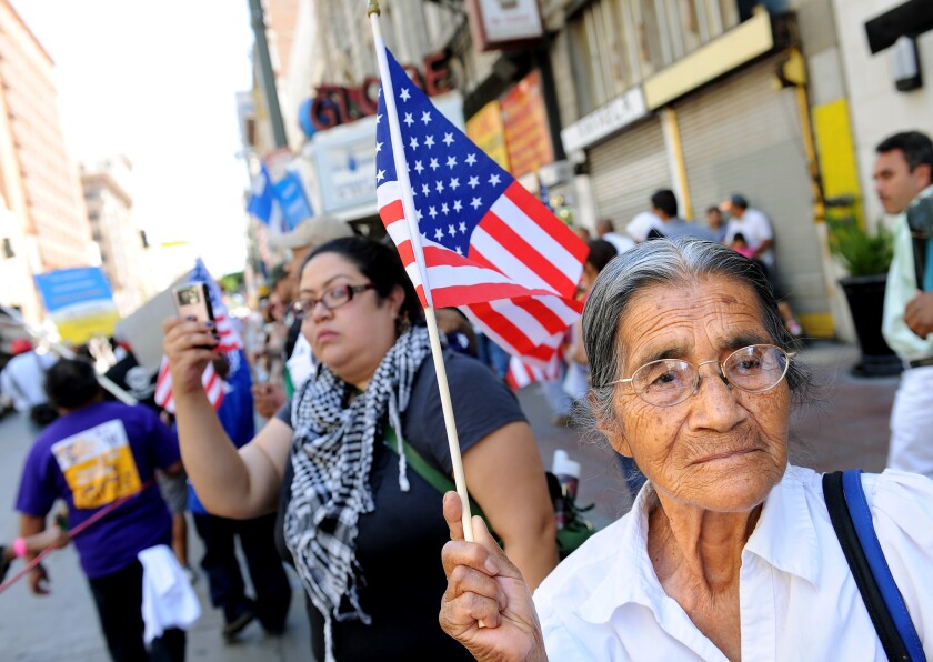 A woman waves a U.S. flag as marchers make their way down Broadway in downtown Los Angeles during a 2011 May Day event calling for immigration reform.