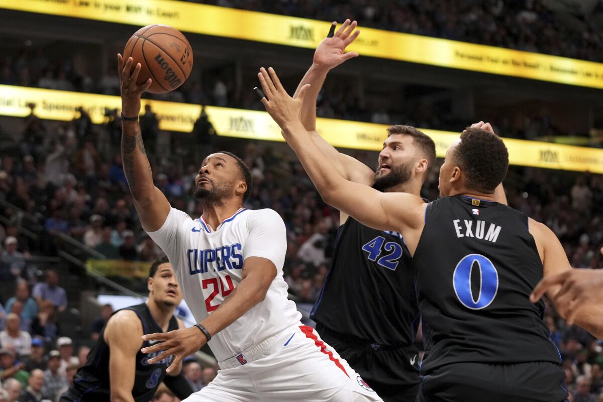 Clippers guardı Norman Powell, Dallas'tan Maxi Kleber (42) ve guard Dante Exum'a (0) karşı turnike yapmaya çalışıyor.