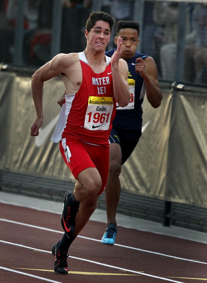 Mater Dei's Curtis Godin, left, sprints past Santa Monica's Marcel Espinoza to win the boys' 100-meter dash on Saturday at the Arcadia Invitational track and field meet.