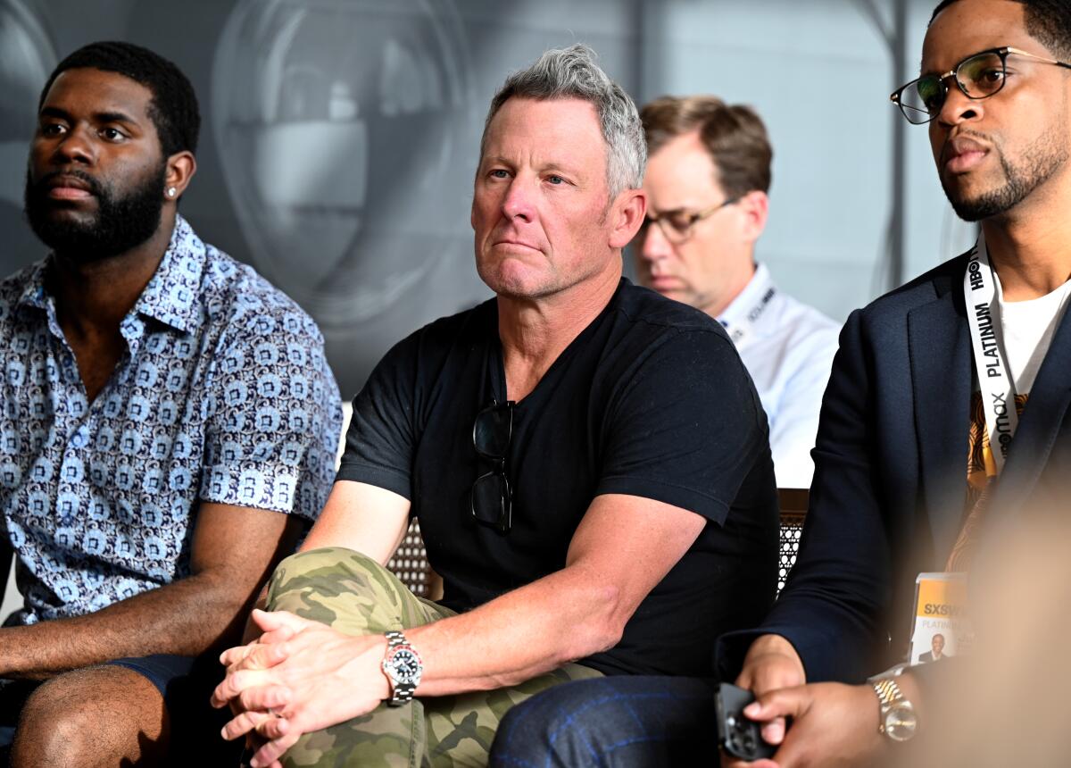 Lance Armstrong, center, and guests listen to a panel discussion 
